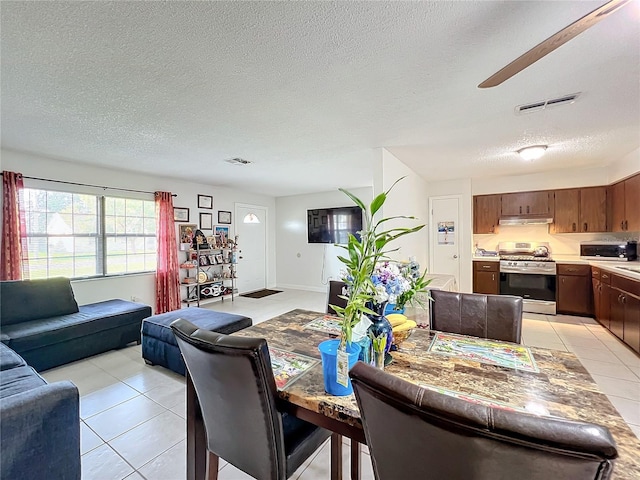 tiled dining room with ceiling fan and a textured ceiling