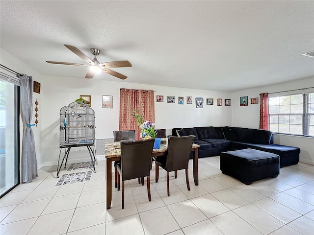 living room with a textured ceiling, light tile patterned floors, and ceiling fan