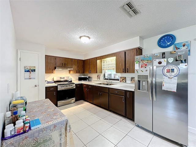 kitchen featuring a textured ceiling, appliances with stainless steel finishes, light tile patterned floors, and sink