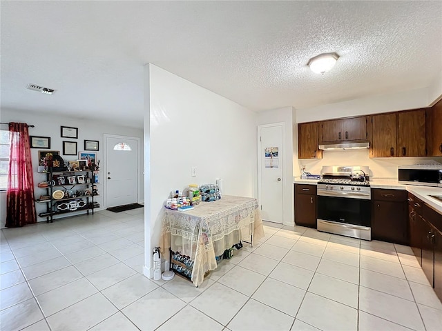 kitchen with light countertops, visible vents, appliances with stainless steel finishes, under cabinet range hood, and light tile patterned floors