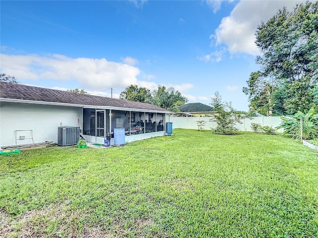 view of yard with a sunroom, central AC, and a fenced backyard