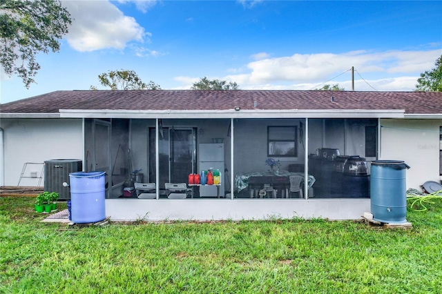 back of house with cooling unit, a sunroom, and a lawn