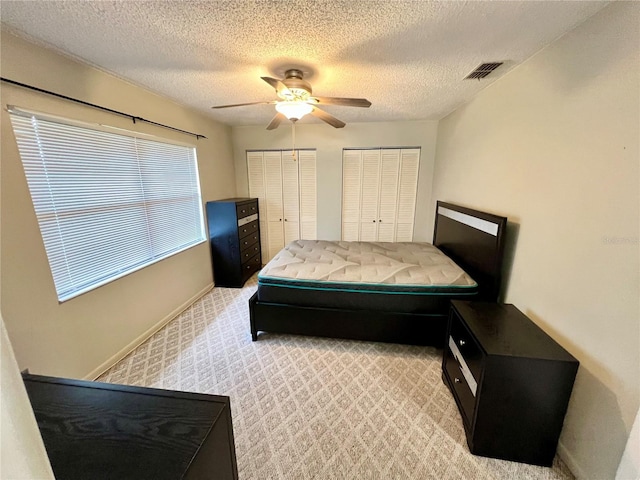 6789 SE 54th Ln, Ocala, FL 34472 - bedroom featuring two closets, light colored carpet, ceiling fan, and a textured ceiling