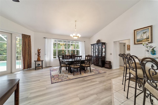 dining space with a notable chandelier, vaulted ceiling, light hardwood / wood-style floors, and plenty of natural light