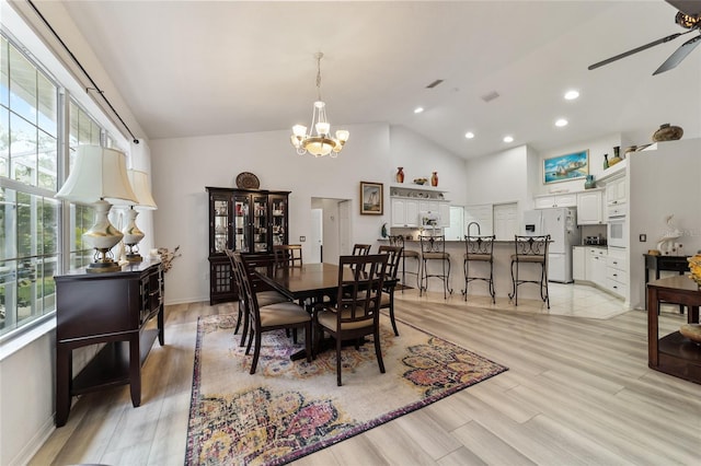 dining space featuring ceiling fan with notable chandelier, light hardwood / wood-style flooring, and high vaulted ceiling