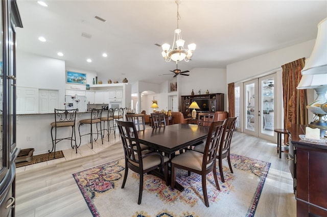 dining space featuring ceiling fan with notable chandelier, light hardwood / wood-style floors, vaulted ceiling, and french doors