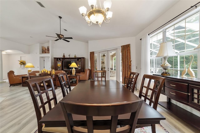 dining space with ceiling fan with notable chandelier, lofted ceiling, and light hardwood / wood-style floors