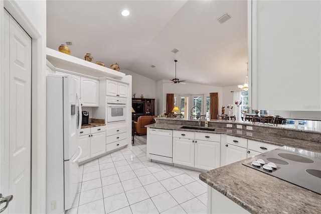 kitchen featuring sink, ceiling fan with notable chandelier, white cabinets, vaulted ceiling, and white appliances