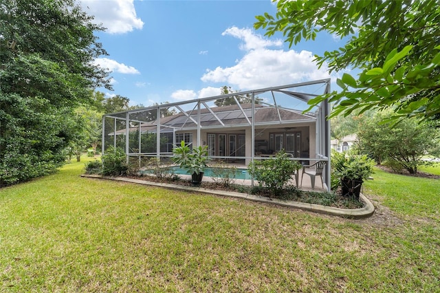 rear view of property with a lawn and glass enclosure