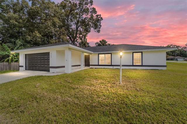 ranch-style house featuring a garage and a lawn