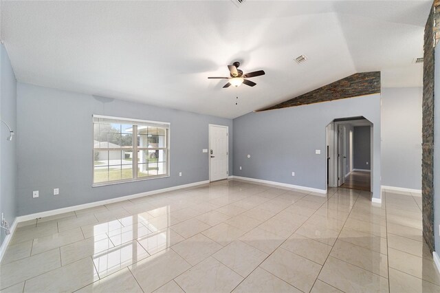 spare room with ceiling fan, lofted ceiling, and light tile patterned floors