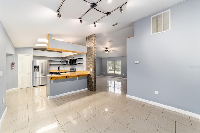 kitchen with wood counters, track lighting, ornate columns, light tile patterned floors, and stainless steel appliances