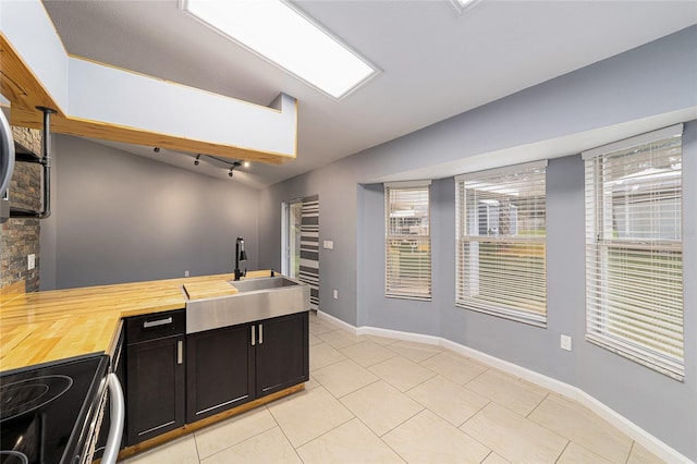 kitchen with butcher block countertops, plenty of natural light, light tile patterned flooring, and stove