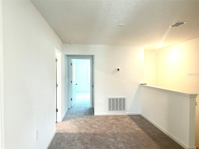 spare room featuring a textured ceiling and carpet flooring