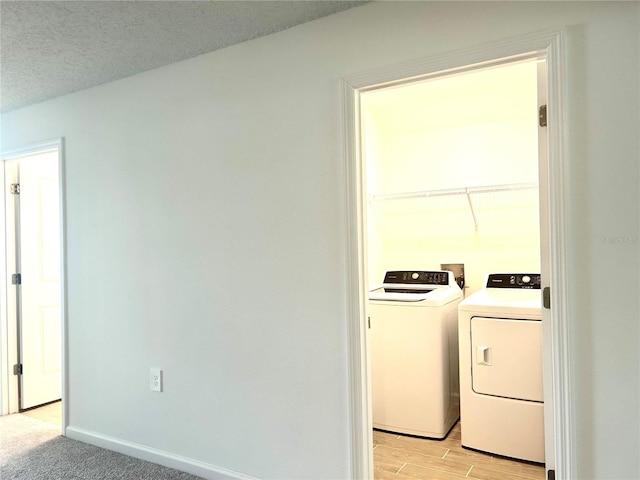 clothes washing area with a textured ceiling, light hardwood / wood-style flooring, and independent washer and dryer