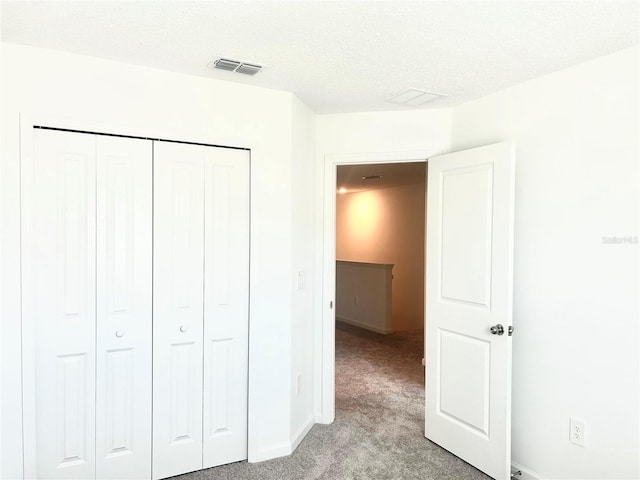 unfurnished bedroom with a closet, light colored carpet, and a textured ceiling