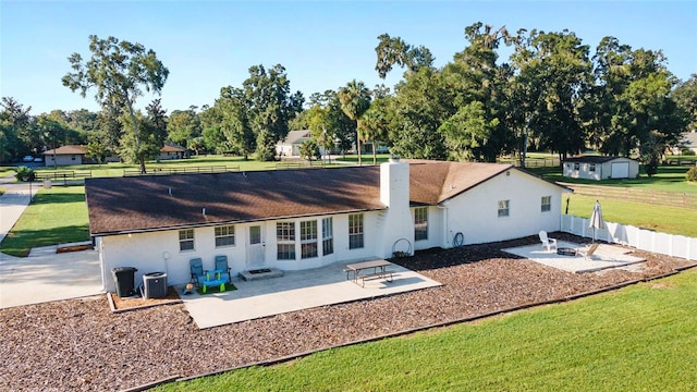 back of house featuring a patio area, a storage unit, a lawn, and central AC unit