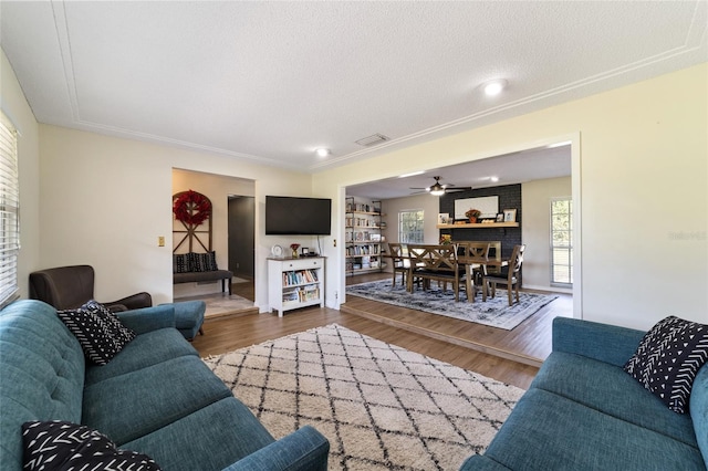 living room featuring ceiling fan, crown molding, a textured ceiling, and dark hardwood / wood-style flooring