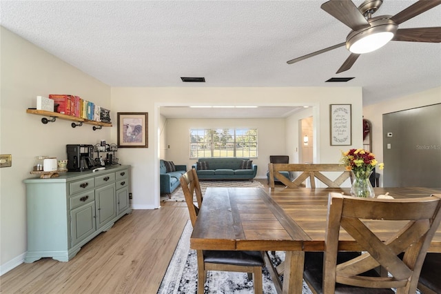 dining room featuring light hardwood / wood-style floors, a textured ceiling, and ceiling fan