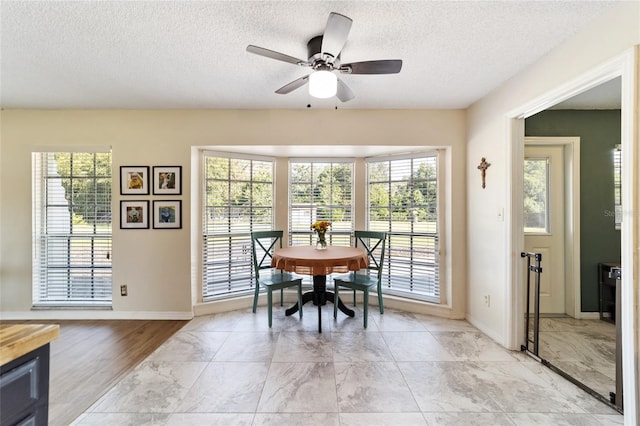 dining area with ceiling fan, a textured ceiling, a wealth of natural light, and light hardwood / wood-style floors