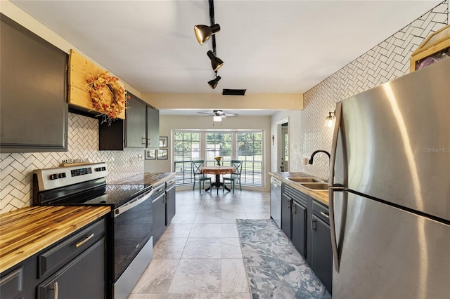 kitchen featuring sink, butcher block counters, ceiling fan, stainless steel appliances, and decorative backsplash