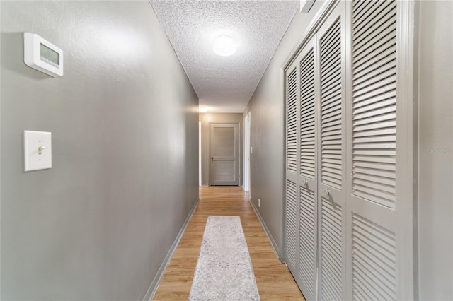 hall featuring light hardwood / wood-style floors and a textured ceiling