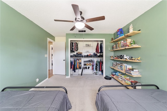 bedroom with a closet, ceiling fan, light carpet, and a textured ceiling