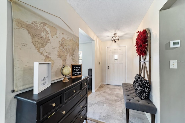 foyer with a textured ceiling, marble finish floor, and baseboards