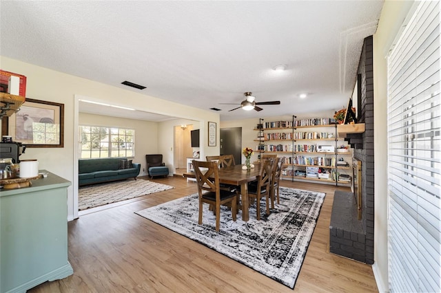 dining room featuring light wood-style floors, ceiling fan, and a textured ceiling