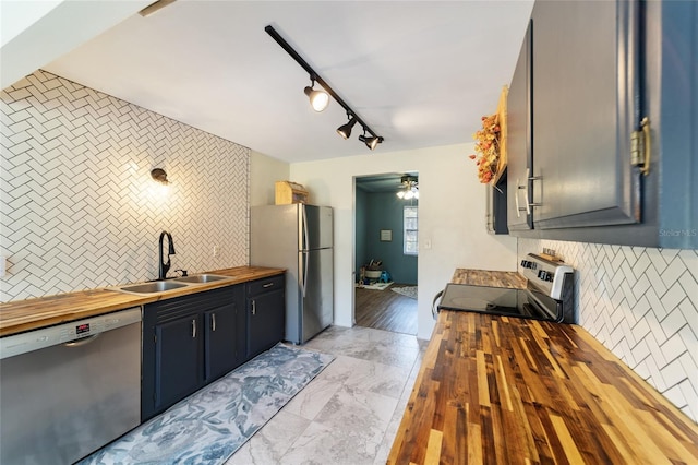 kitchen with decorative backsplash, marble finish floor, stainless steel appliances, wooden counters, and a sink