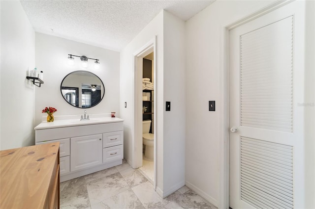 bathroom featuring a textured ceiling, marble finish floor, vanity, and toilet