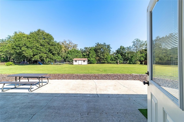 view of patio featuring an outbuilding, a shed, and fence