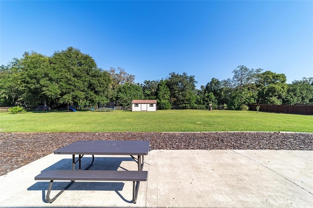 view of patio / terrace with an outbuilding, a storage unit, and fence