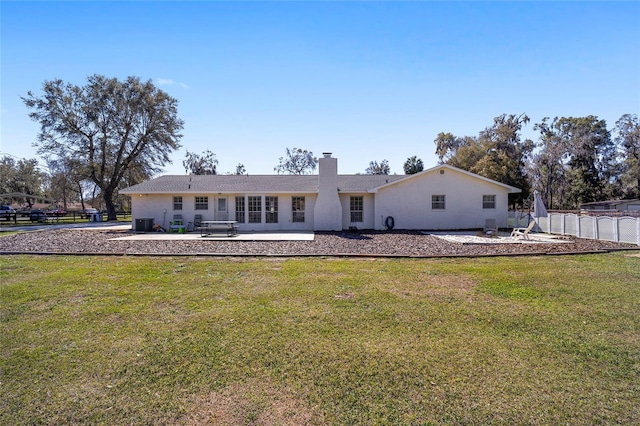 back of house featuring a yard, fence, a chimney, and stucco siding