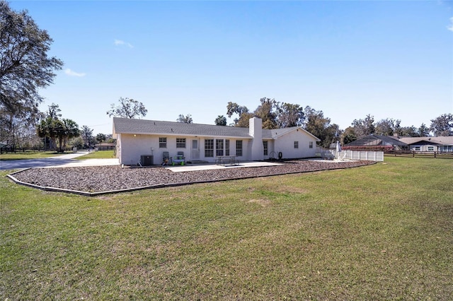 rear view of house with a chimney, fence, central AC, and a yard