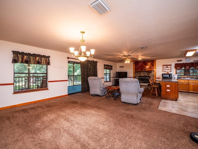 carpeted living room with ceiling fan with notable chandelier, a textured ceiling, and a fireplace