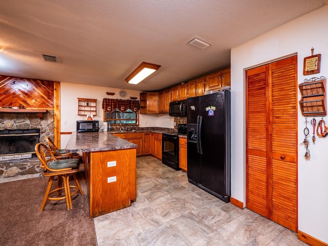 kitchen with a breakfast bar area, kitchen peninsula, a textured ceiling, and black appliances