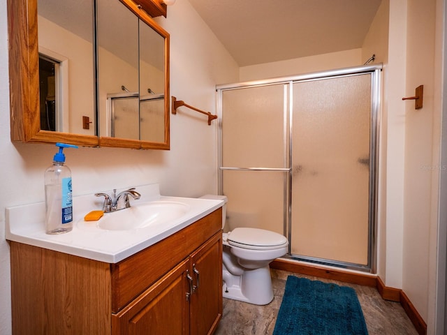 bathroom featuring a shower with door, vanity, and toilet