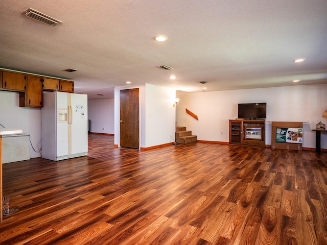 unfurnished living room featuring a textured ceiling and dark wood-type flooring