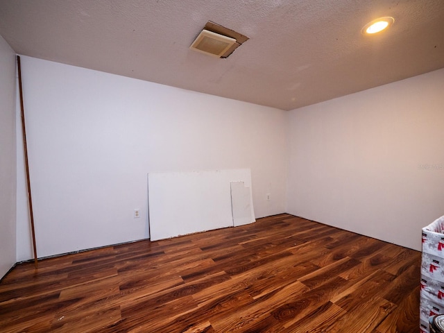 unfurnished room featuring a textured ceiling and dark wood-type flooring