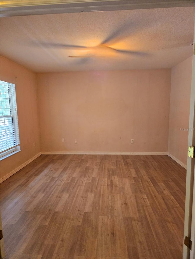 empty room with wood-type flooring and a textured ceiling