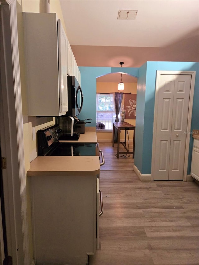 kitchen featuring hanging light fixtures, white cabinets, kitchen peninsula, light wood-type flooring, and electric range