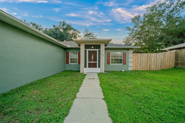 view of exterior entry featuring a lawn