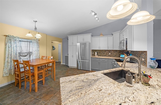 kitchen featuring appliances with stainless steel finishes, white cabinetry, vaulted ceiling, tasteful backsplash, and sink