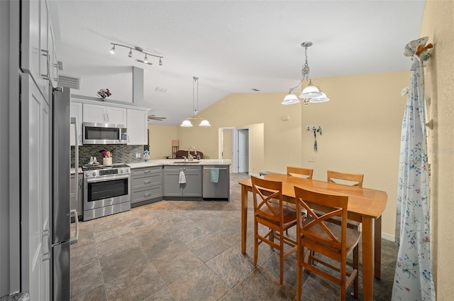 kitchen with gray cabinets, sink, lofted ceiling, appliances with stainless steel finishes, and decorative light fixtures