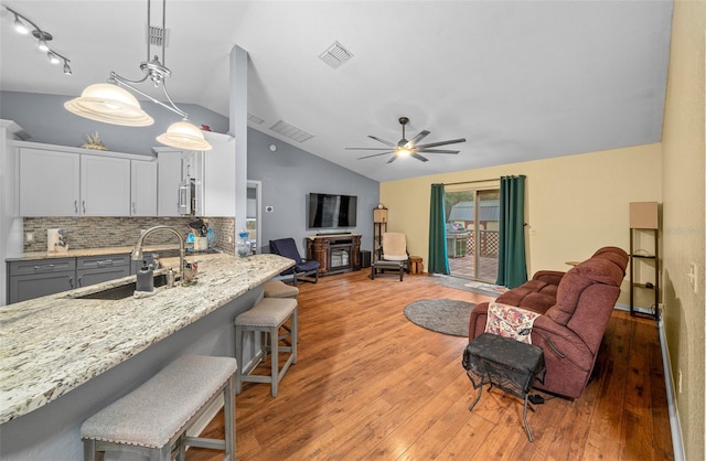 interior space featuring ceiling fan, lofted ceiling, light wood-type flooring, and sink