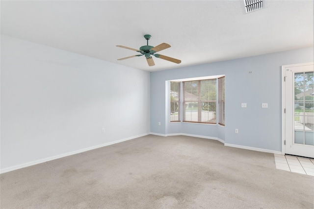 empty room featuring ceiling fan, light colored carpet, and a healthy amount of sunlight