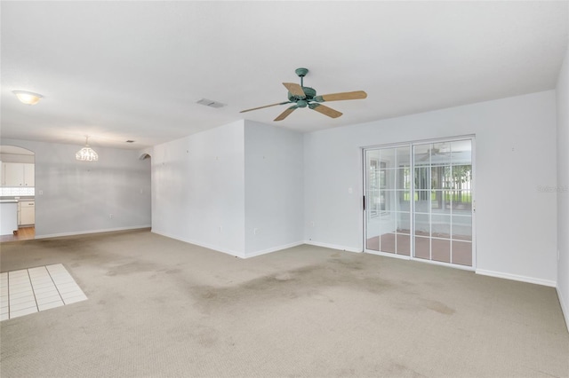 carpeted spare room with ceiling fan with notable chandelier