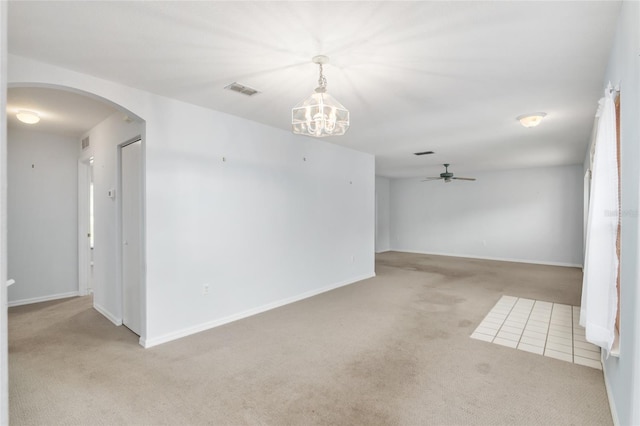 carpeted spare room with ceiling fan with notable chandelier