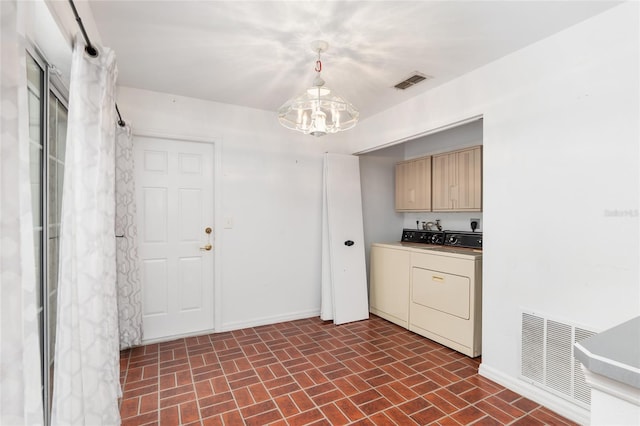 laundry room with a chandelier, washer and dryer, and cabinets